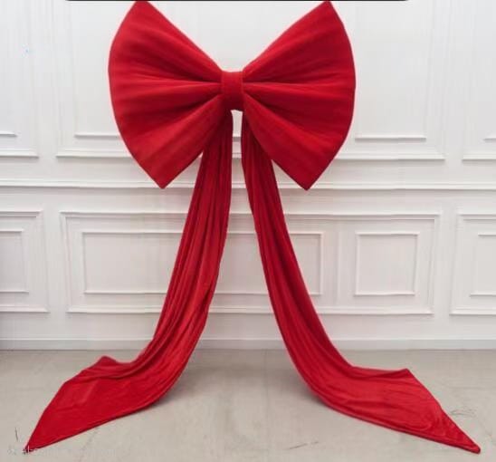 Large red velvet bow against a white paneled wall